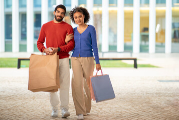 Full Length Of Diverse Couple Walking With Shopping Bags Outside