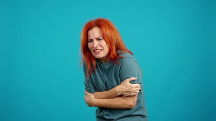 Mature redheaded woman looking at camera gesturing she is cold
