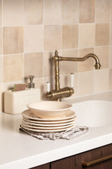 Sink, brass faucet, clean washed dishes. Stylish kitchen.