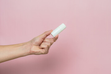 Drops bottle for eye or ear in hand on pink background. Pharmaceutical product. Copy space.