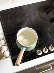 Eggs in boiling water in a saucepan on the stove. 
Induction cooker.
