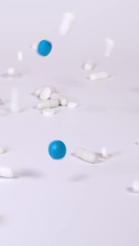 White and blue pharmaceutical products, tablets, pills and capsules falling down against white background. Concept of healthcare, medicine, pharmacy and drugs. Treatment and prevention of diseases.