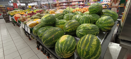 fruits on the supermarket counter. The boxes contain: watermelons, melons, bananas, red apples and oranges.
