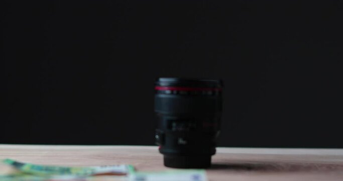 Blurred Camera lens being showered in money with simple black background. High quality 4k footage