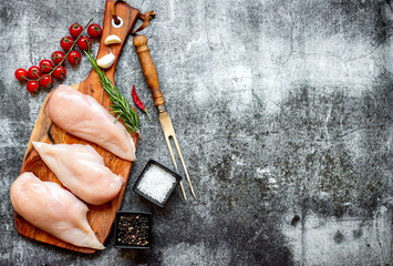 three raw chicken breasts on stone background