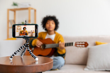 Blogger guitarist. African american girl blogger playing guitar talking to webcam recording vlog....