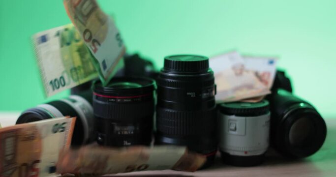 euro bills being thrown at name brand camera photo lense, green background. High quality 4k footage