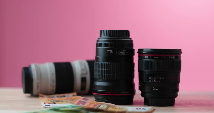 Camera lenses showered in a lot of euro paper money, red studio Background. High quality 4k footage