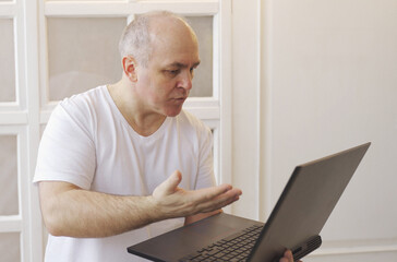 A man with a laptop in his hands has a lively conversation on a video call