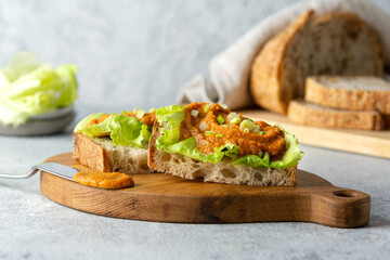 Healthy vegetarian food. Toasted bread sandwich with zucchini caviar, lettuce and green onions on a wooden board. Diet vegan appetizer.