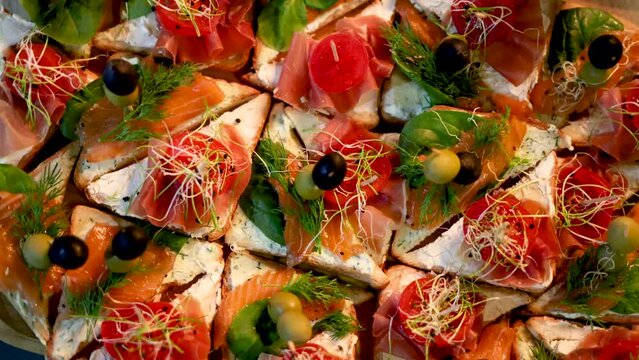 fourchette table in a nightclub or restaurant with tasty delicious dishes,cheese asorti,fruits,spread with prosciutto,olive,jelly colorful cake.dark walls pour light condition 4k rotating spinning