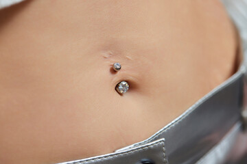 Closeup of a belly button naval that is pierced with jewelry.