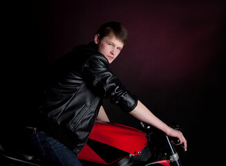 Obraz na płótnie Canvas Man, guy in black leather jacket sits on motor bike in studio, motorbike