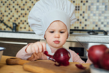 Little girl Cooking in the kitchen wearing an apron and a Chef's hat.