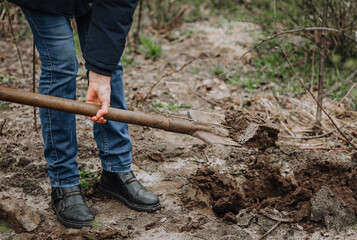 Woman gardener digs a hole with a shovel on brown ground outdoors, in nature in the garden. Photography, close-up, gardening concept, portrait.