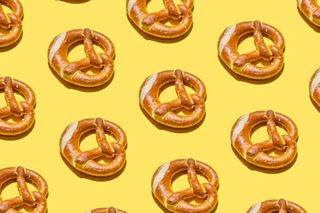 Fresh soft pretzels, creative food pattern, yellow background. 