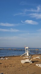 The beach of the Mediterranean Sea. There are deck chairs and a rescue point on the shore. Beautiful view of the sea and clouds. Rest at the sea, relax. Vacation