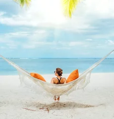 Zelfklevend Fotobehang Young woman relaxing in wicker hammock on the sandy beach on Mauritius coast and enjoying wide ocean view waves. Exotic countries vacation and mental health concept image. © Soloviova Liudmyla