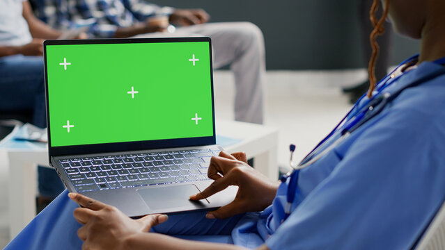 Medical Assistant Looking At Wireless Pc With Greenscreen, Analyzing Chroma Key Display In Waiting Room. Specialist Working With Blank Mockup Template And Isolated Copyspace, Health Care.