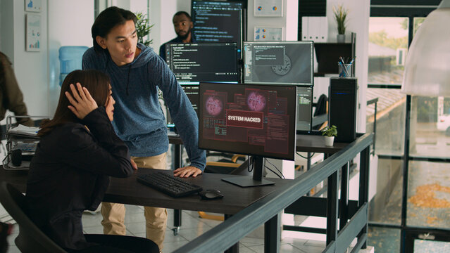 Diverse team of artificial intelligence cloud programers being hacked on firewall server. Web developers looking at critical error on software html script, doing teamwork in agency office.