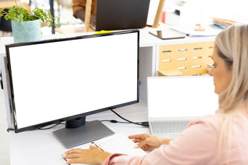 Focused casual caucasian businesswoman using computer with copy space in modern office