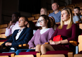 caucasian family sitting at premiere in theatrical hall