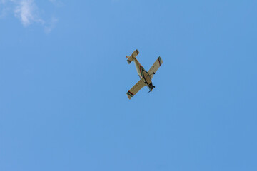 A small four-seater light plane flies in the clear sky. View from below.