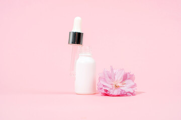 Fototapeta na wymiar White serum dropper bottle and sakura flower on pink background. Skin care, beauty treatment concept. Mockup