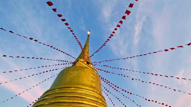 Low angle shot of golden stupa and red flags and blue sky with clouds