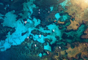 Top drone view of boats and yacths in transparent azure water at sunset. Aerial view of boats in...