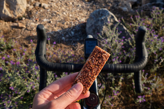Cycling snack.Sports snack for cyclist.A sports bar in the hand of a cyclist against the background of a bicycle.Energy sports bar.