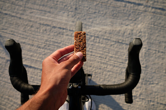 Cycling snack.Sports snack for cyclist.A sports bar in the hand of a cyclist against the background of a bicycle.Energy sports bar.
