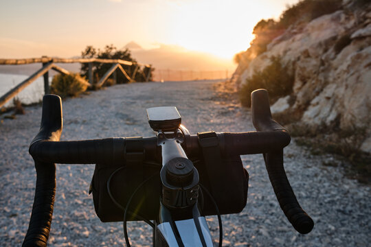Gravel bike handlebar view with bike computer and handlebar bag overlooking mountains