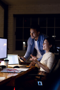 Diverse happy business people using computer, working late at office, with copy space