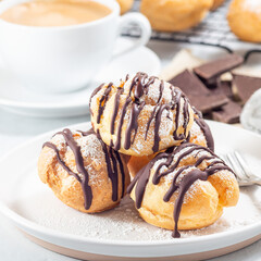 Profiteroles with whipped cream and chocolate filling, covered with melted chocolate, square