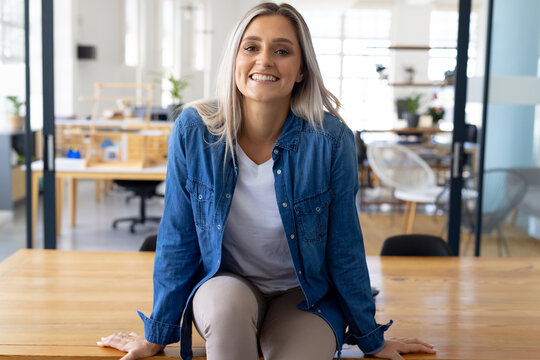 Portrait of casual happy caucasian businesswoman looking at camera in modern office