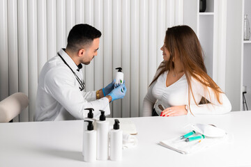 A Handsome, confident doctor explains and showing a blank white bottle with a medicine to a female patient. copy space.