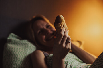 Penis size concept. The woman smiles and holds in her hands a bun that looks like a male phallus.