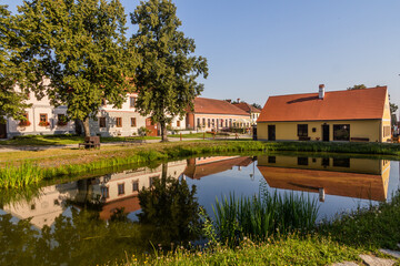 Obraz premium Pond and traditional houses of rural baroque style in Holasovice village, Czech Republic