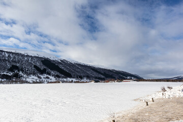Frozen river valley with mountains on background. Norway.