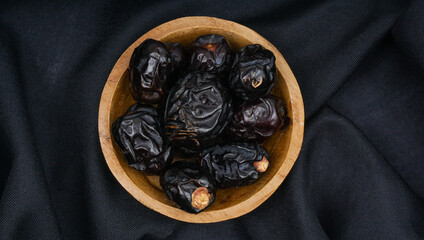 Delicious ajwa dates ( kurma nabi ) or Prophet's Dates. Kurma Ajwa over black fabric texture