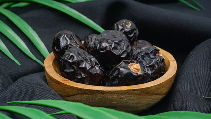 Delicious ajwa dates ( kurma nabi ) or Prophet's Dates. Kurma Ajwa over black fabric texture