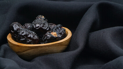 Delicious ajwa dates ( kurma nabi ) or Prophet's Dates. Kurma Ajwa over black fabric texture