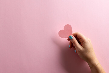 Image of woman holding pink heart with copy space on pink background