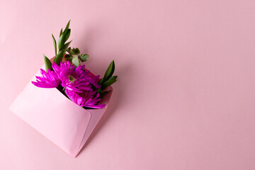 Image of pink flowers in pink envelope with copy space on pink background
