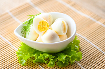 boiled eggs food, quail eggs on white bowl, breakfast eggs with fresh quail eggs and vegetable lettuce on table background