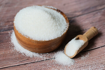Fototapeta na wymiar Sugar on spoon and wooden bowl, white sugar for food and sweets dessert candy heap of sweet sugar crystalline granulated