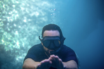 Fototapeta na wymiar young man under the sea with goggles and snorkel looking at the camera