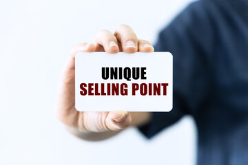 Unique selling point text on blank business card being held by a woman's hand with blurred background. Business concept about unique selling point.