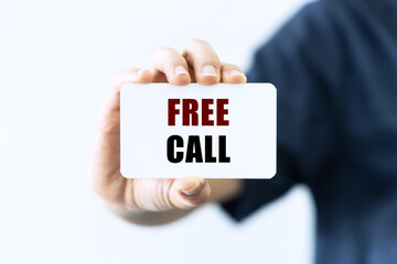 Free call text on blank business card being held by a woman's hand with blurred background. Business concept about free call.